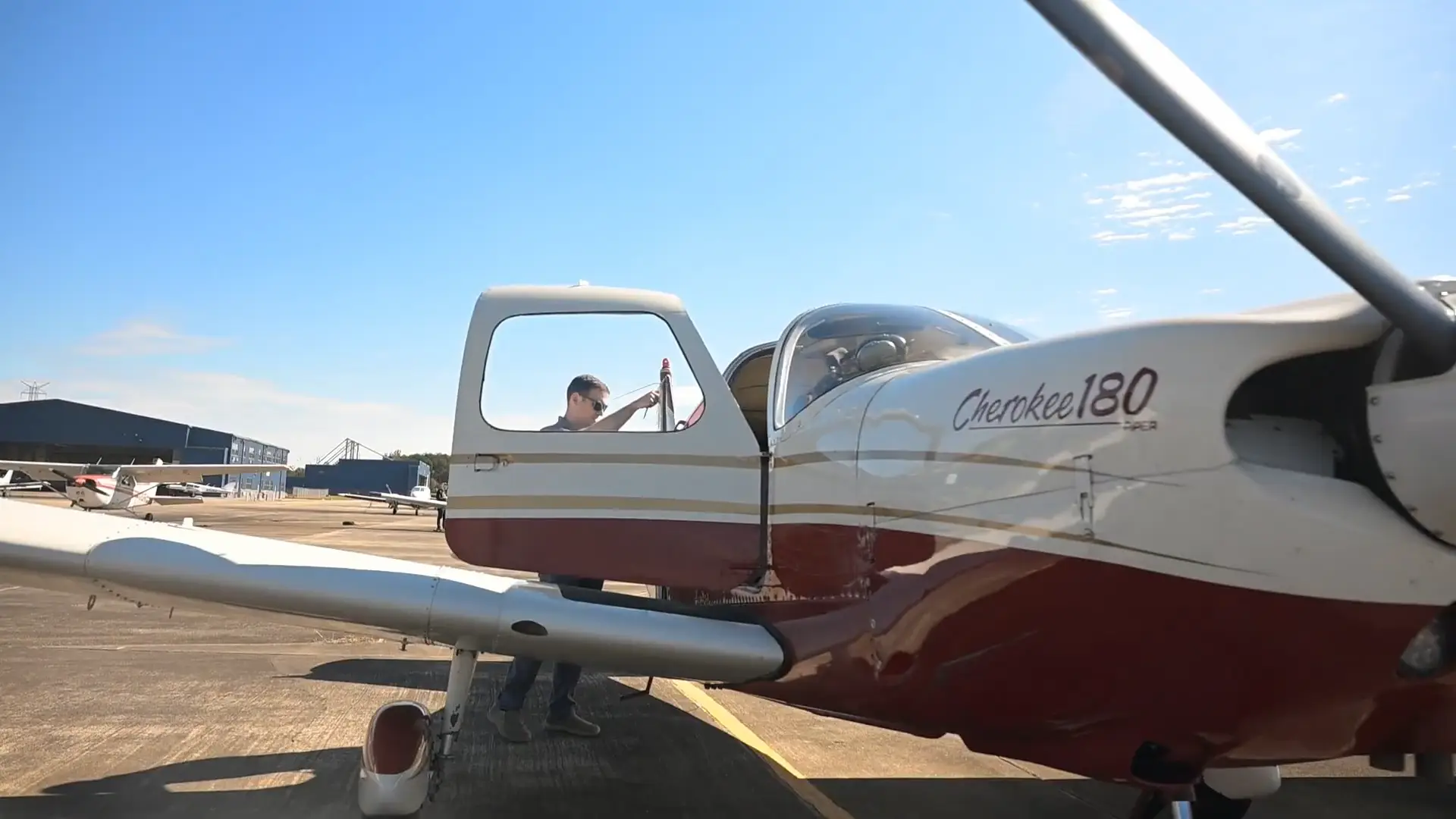 Pilot standing next to the training aircraft with the doors open at Tipton Airport