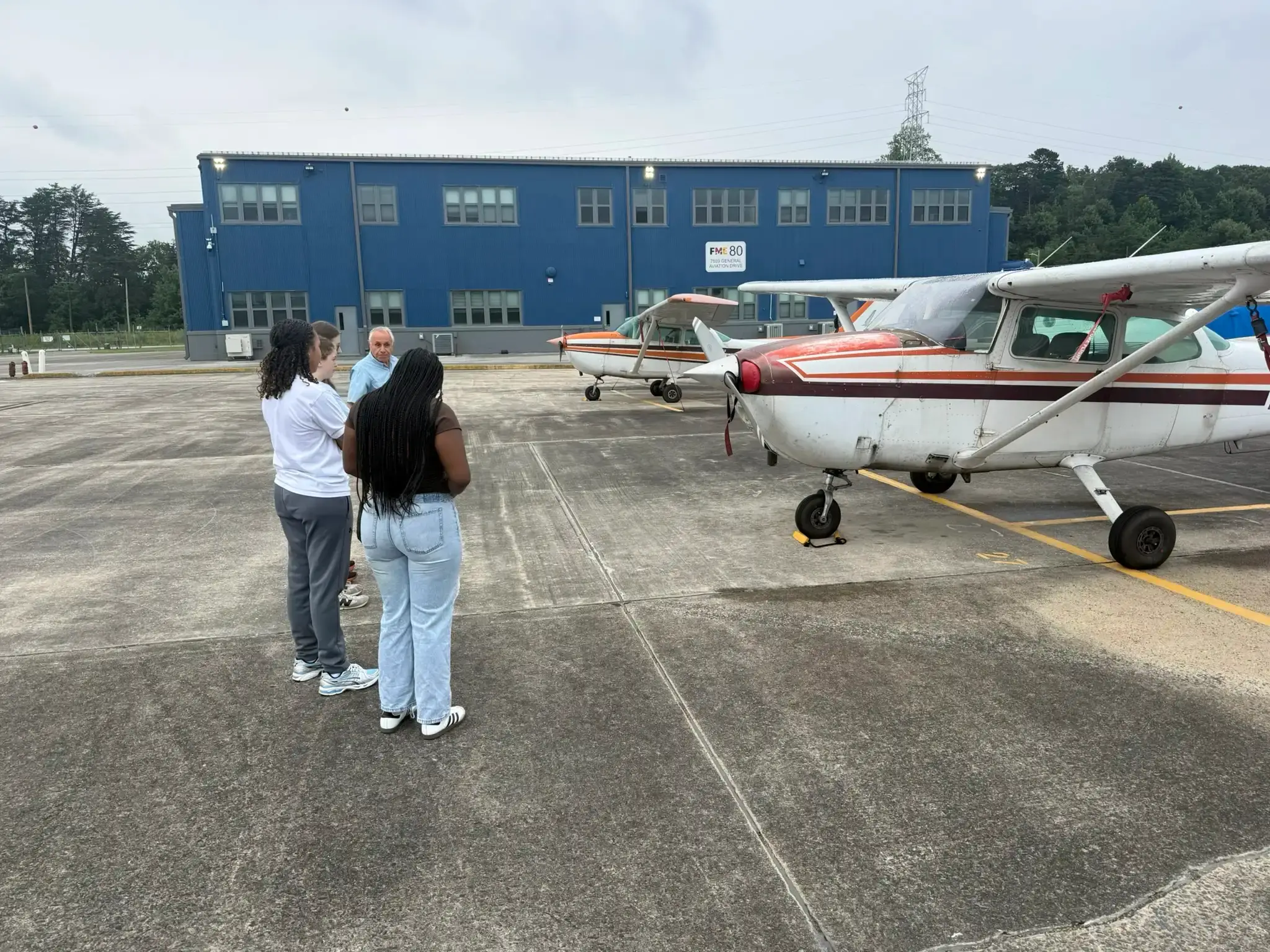Campers talking with a flight instructor on the ramp beside two Cessna 172s at Tipton Airport