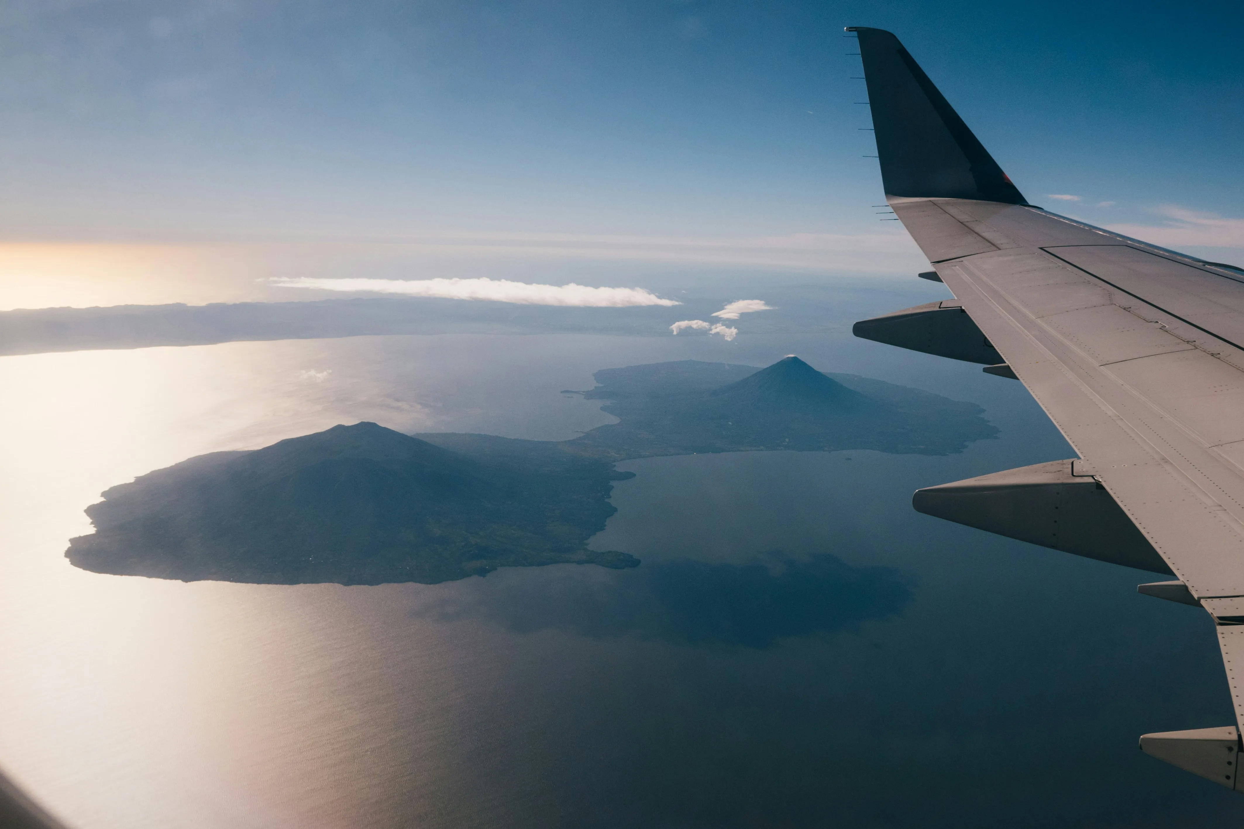 View of islands and an airplane's left wing from above through an airplane window