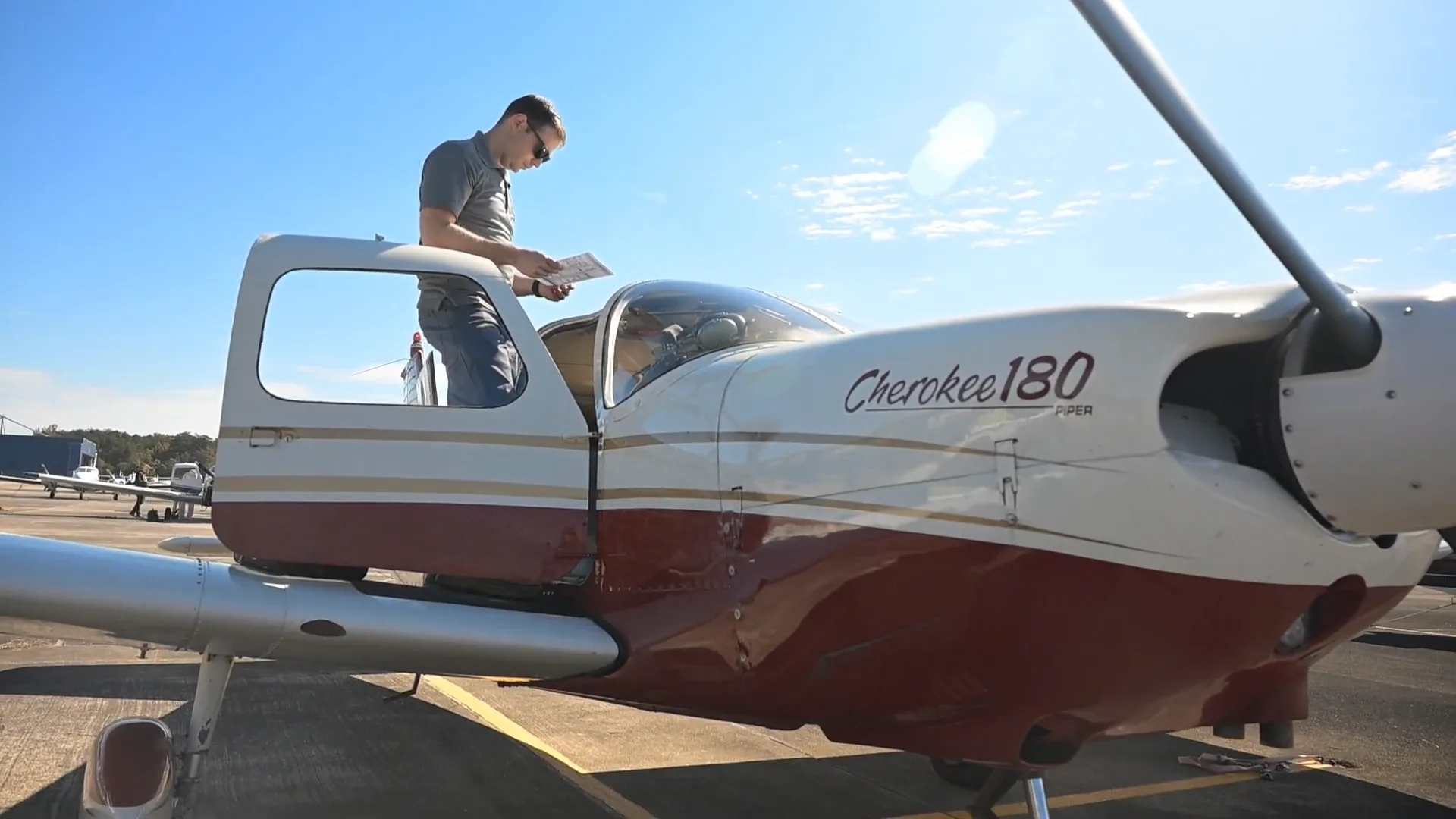 Pilot reading a chart on top of the airplane wing before a flight